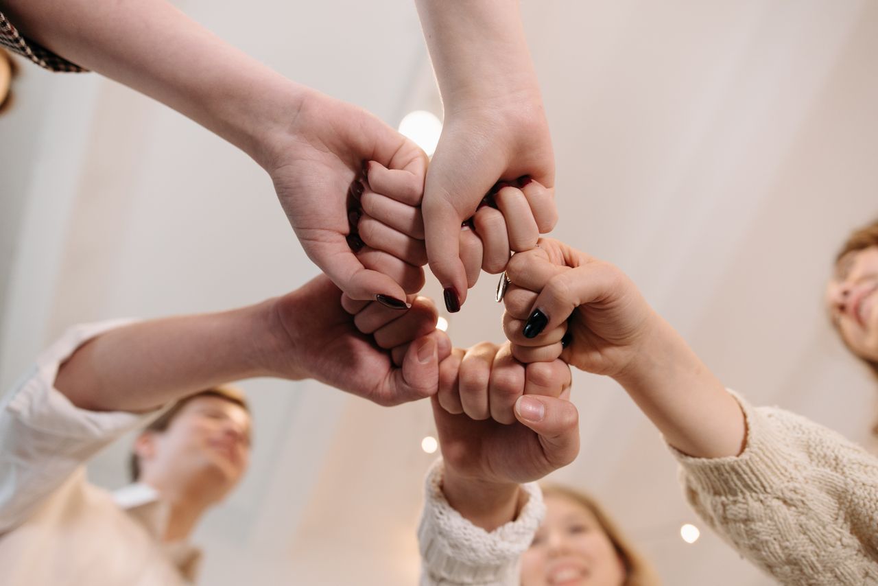 The Art of Drawing Readers In: Your attractive post title goes here Close-up of a diverse group joining fists in a show of unity and teamwork indoors.